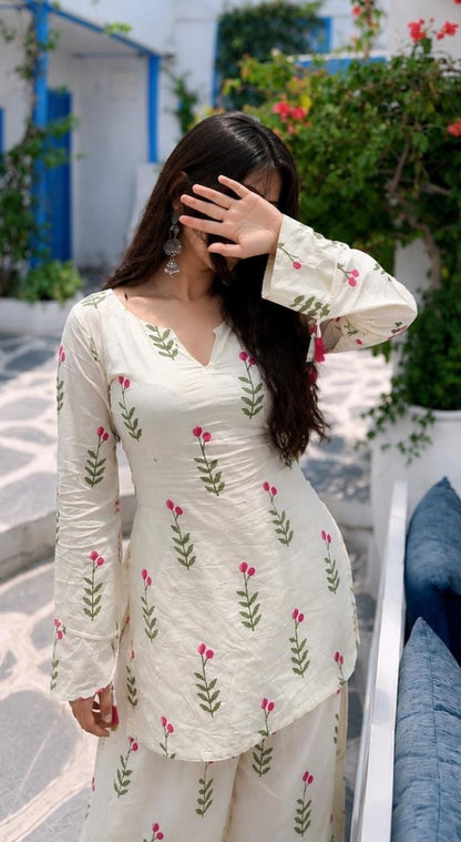 A woman wearing a cream-colored Fasrshi kurta set with pink floral prints and green leafy stems