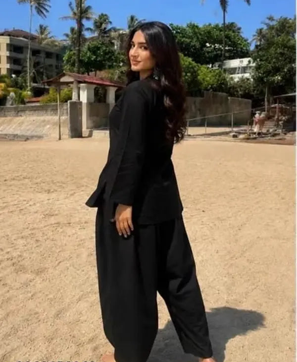 A woman wearing a black two-piece Farshi suit Salwar with a long-sleeve Kurta and wide-leg pants,