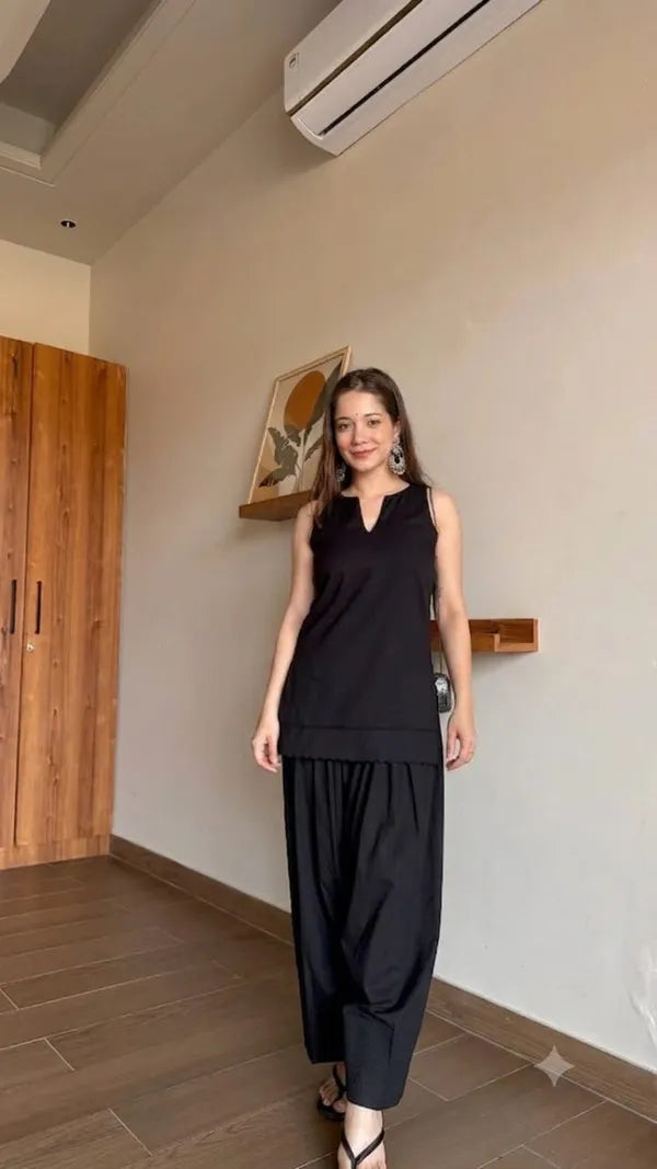 A woman modeling a black sleeveless Farshi Suit and wide-leg black Farshi Salwar pants 