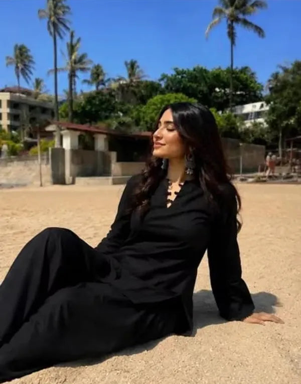 A woman wearing a black long-sleeve Farshi Kurta and black Farshi pants 