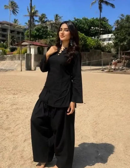A woman wearing a black two-piece Farshi Suit outfit with a long-sleeve kurta and wide-leg Farshi pants, 