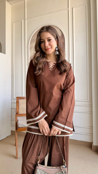 A woman modeling a brown long-sleeve Farshi Suit with white striped cuffs and a lace-up neckline, paired with matching brown Farshi Salwar bottoms