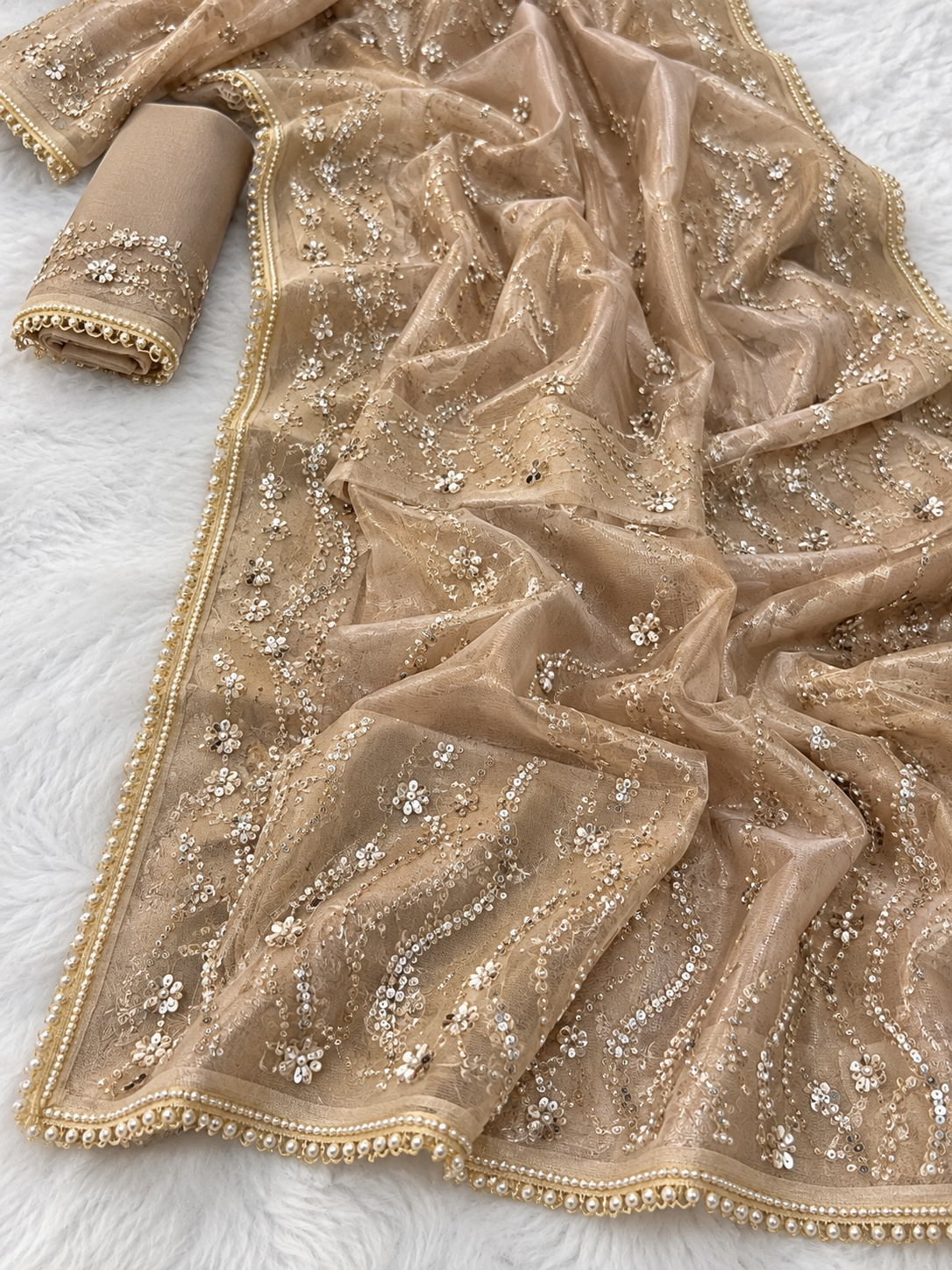 Golden Champagne Net Saree for Women, Pearl and Sequin Embroidered Designer Saree .sheer organza dupatta with intricate silver and gold floral embroidery and beadwork, displayed on a white faux fur background next to a matching rolled sleeve.