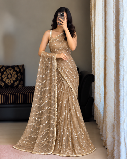 Golden Net Saree Pearl Sequin Embroidered .woman takes a mirror selfie wearing a floor-length beige embellished saree with a matching dupatta in an indoor setting.