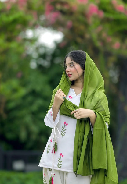 A woman wearing a white embroidered Farshi Kurta set with a green shawl draped over her headflowers.