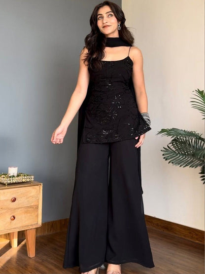 A woman modeling a black sleeveless Kurti with a halter-style neck and matching wide-leg Sharara